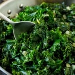 A pan of sauteed kale with a serving spoon in it.