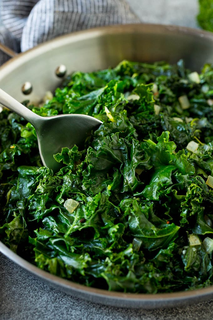 A pan of sauteed kale with a serving spoon in it.