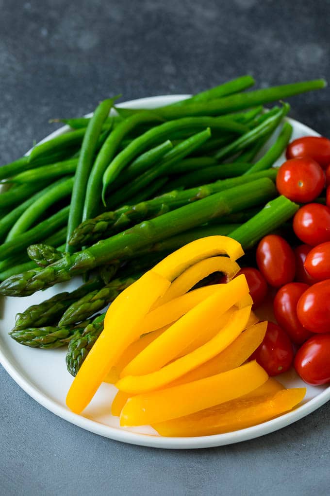 Bell peppers, asparagus, tomatoes and green beans on a plate.