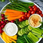 A large veggie tray with assorted fresh and steamed vegetables, ranch dip and hummus.