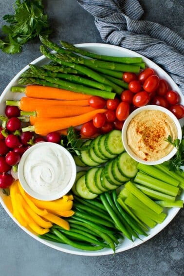 A large veggie tray with assorted fresh and steamed vegetables, ranch dip and hummus.