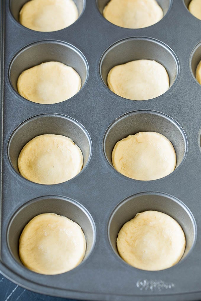 Dough circles pressed into muffin cups.