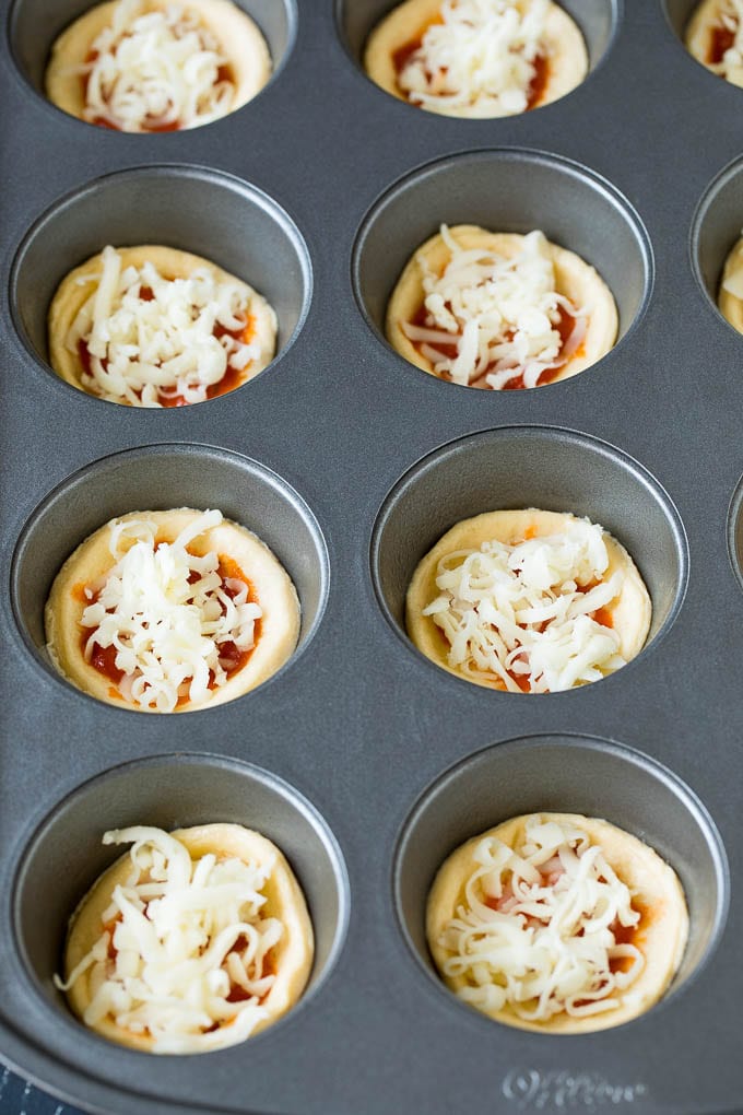 Circles of dough topped with pizza sauce and shredded cheese.