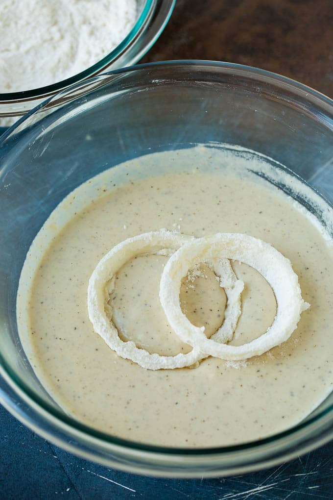 Floured onions in a bowl of beer batter.