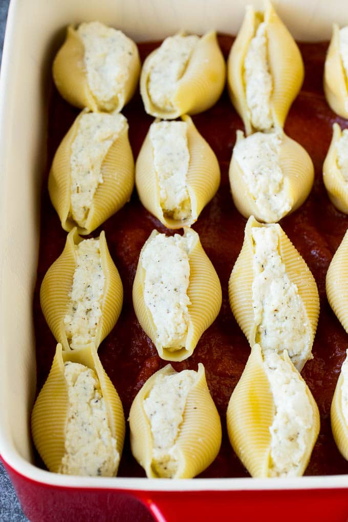 Pasta shells filled with cheese on a bed of tomato sauce.