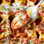 A spoon holding up stuffed shells filled with cheese.