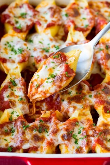 A spoon holding up stuffed shells filled with cheese.