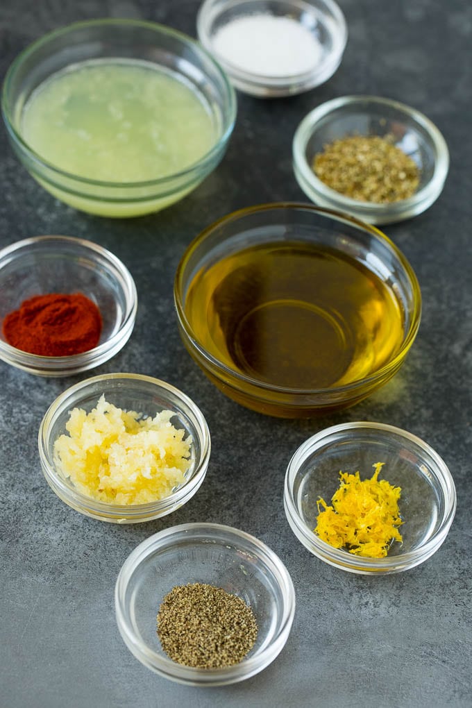 Bowls of lemon juice, olive oil, herbs and spices to make chicken marinade.