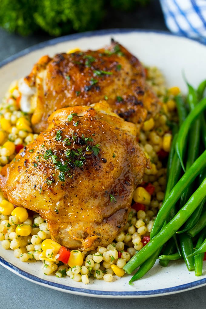 Baked chicken thighs served over couscous with a side of green beans.