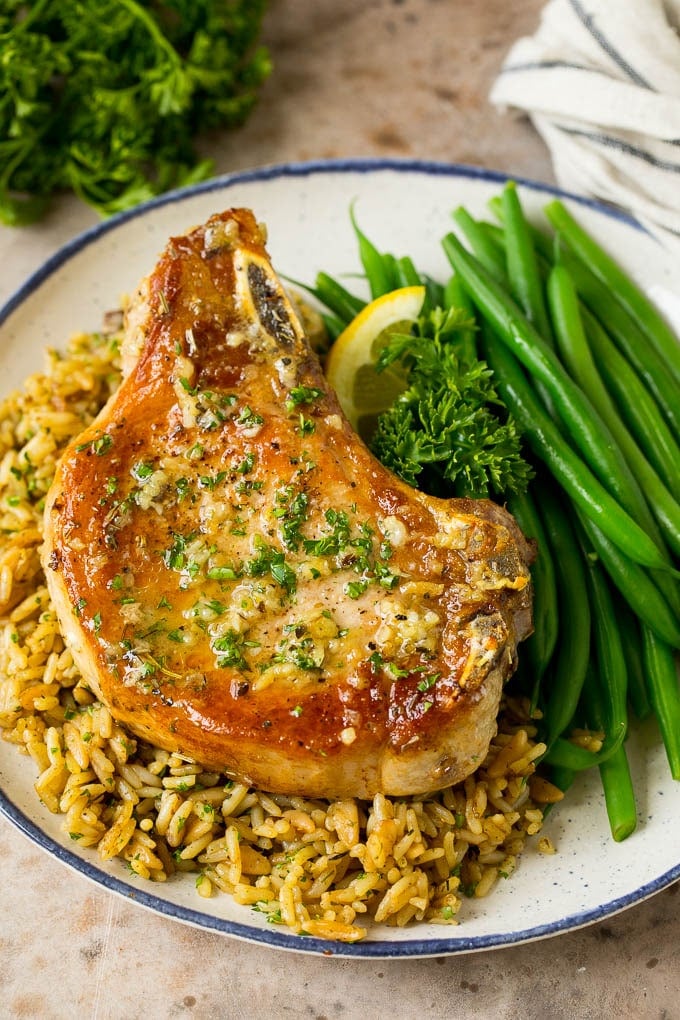 A baked pork chop served over rice with a side of green beans.