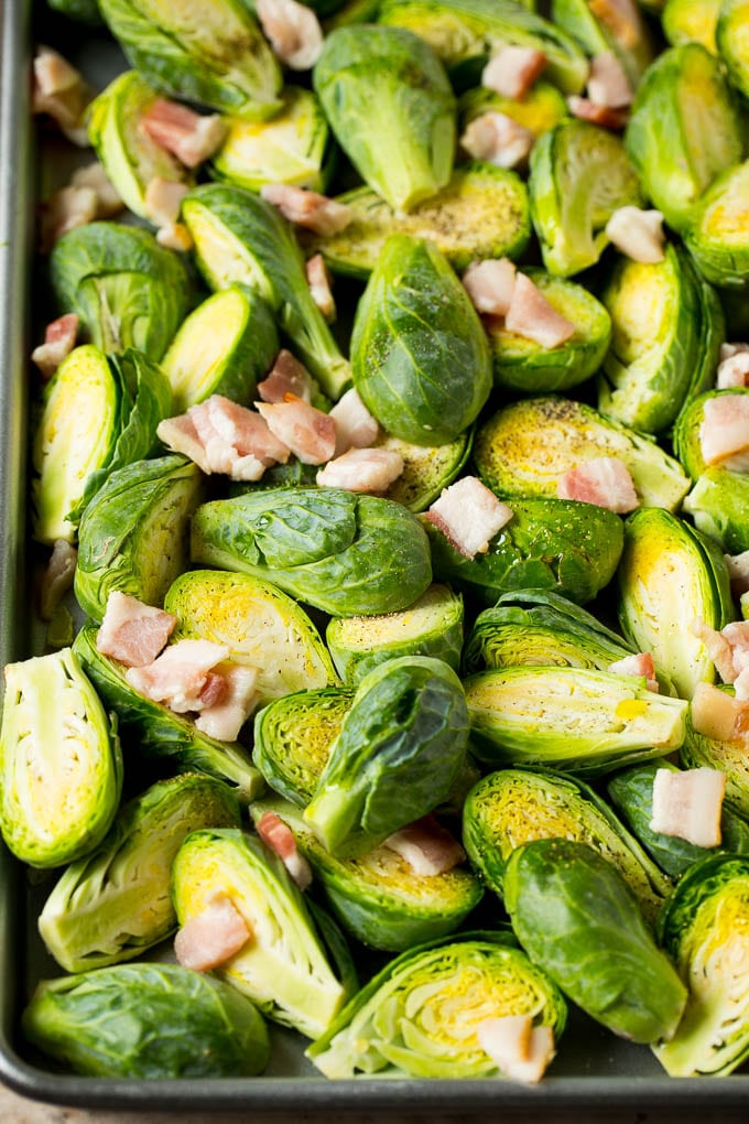 Brussels sprout halves and chopped bacon on a sheet pan.