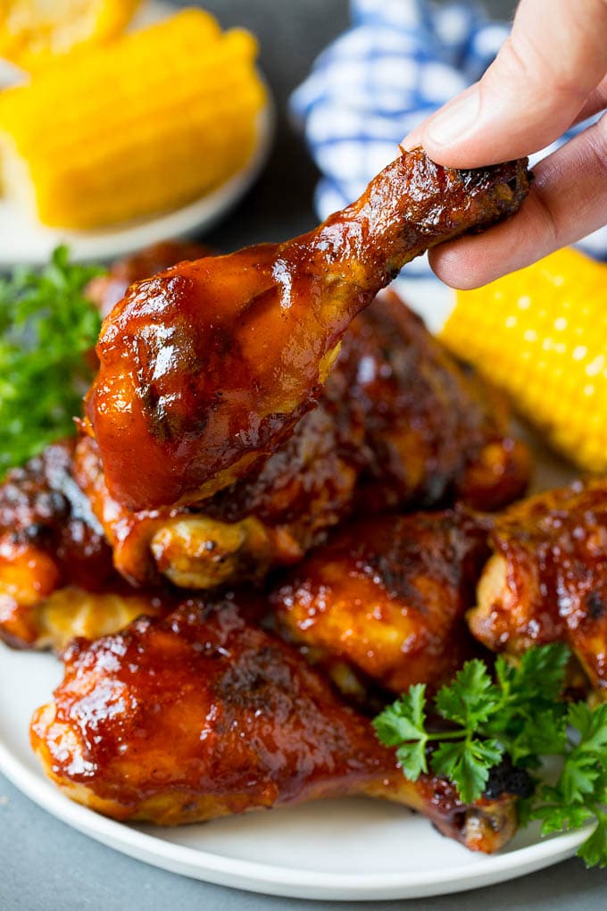 A hold holding a BBQ chicken drumstick.
