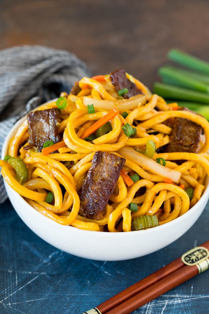 A bowl of beef lo mein topped with green onions.