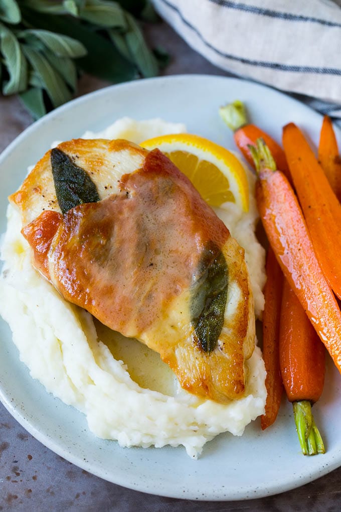 Chicken saltimbocca served over mashed potatoes with carrots on the side.