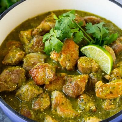 A pot of chile verde topped with cilantro and lime wedges.