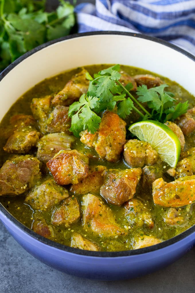 A pot of chile verde topped with cilantro and lime wedges.