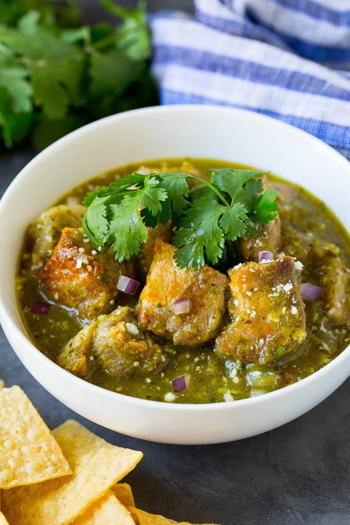 A bowl of pork chile verde garnished with red onion and cilantro.