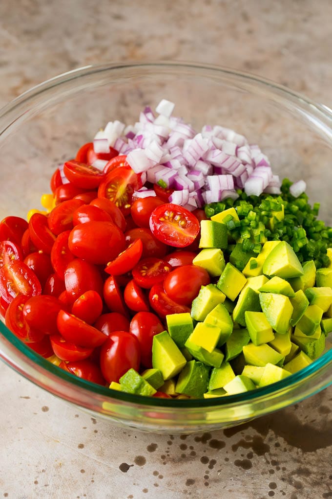 Corn, tomatoes, avocado, jalapeno and red onion in a bowl.