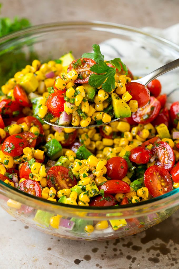A spoon serving up a portion of corn salad.
