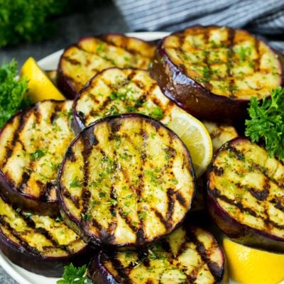 A platter of grilled eggplant garnished with lemon and parsley.