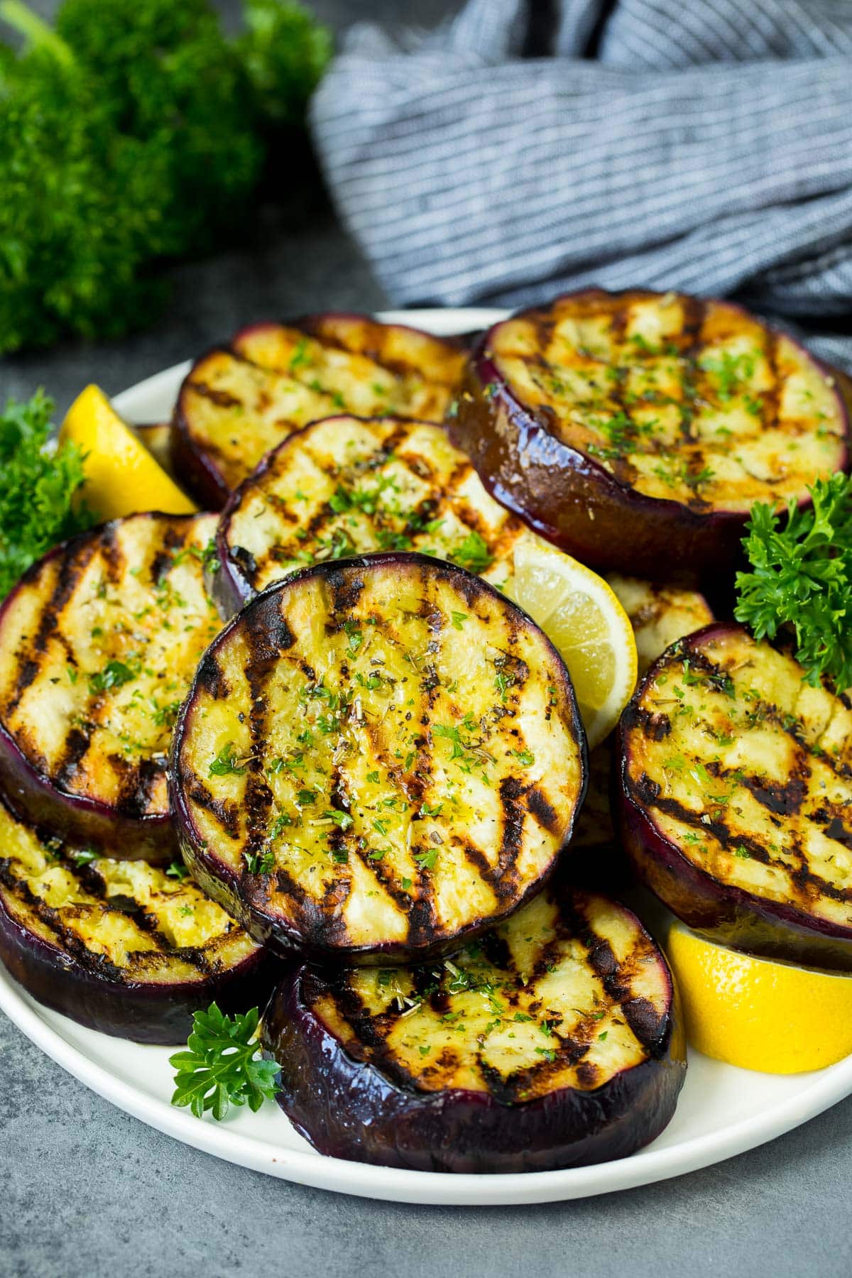 A platter of grilled eggplant garnished with lemon and parsley.
