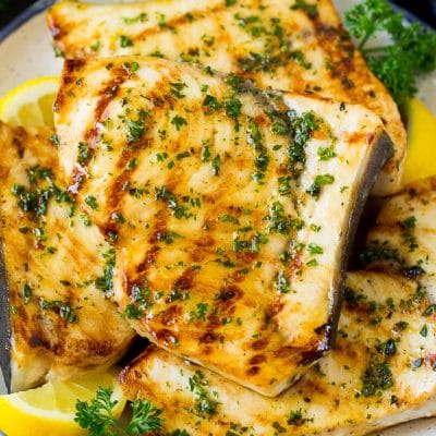 A plate of grilled swordfish steaks topped with herbs.