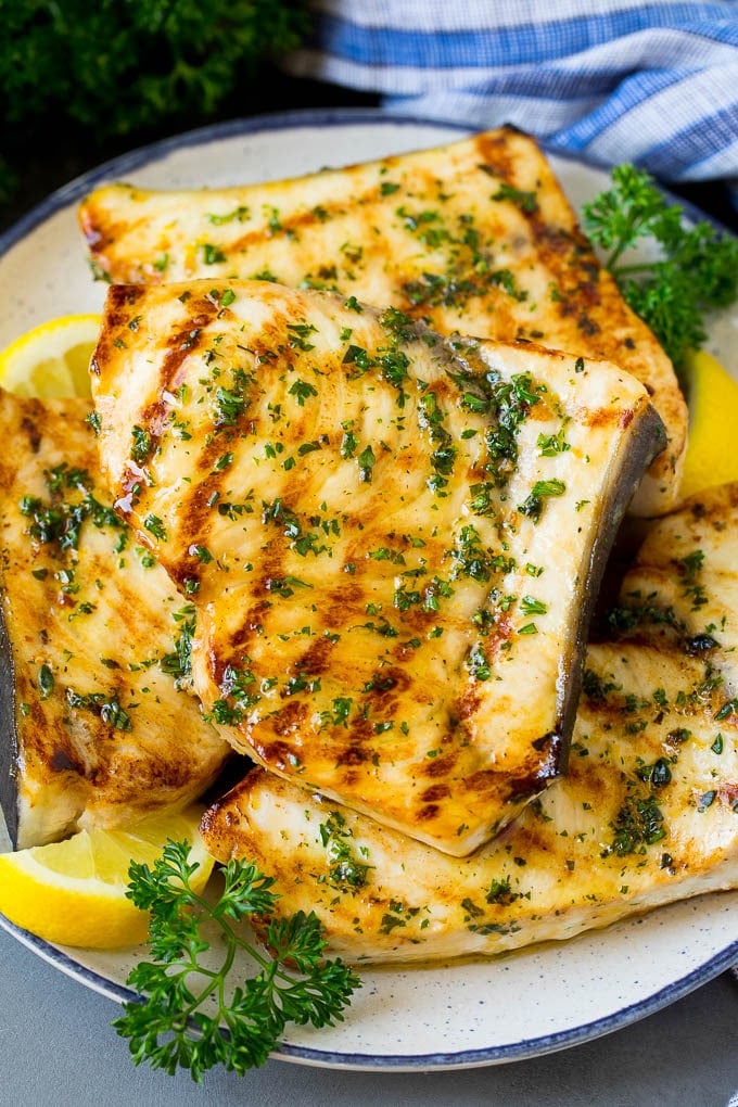 A plate of grilled swordfish steaks topped with herbs.