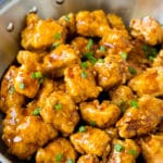 A pan of crispy honey chicken garnished with green onions.