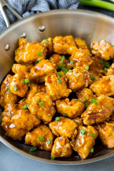 A pan of crispy honey chicken garnished with green onions.