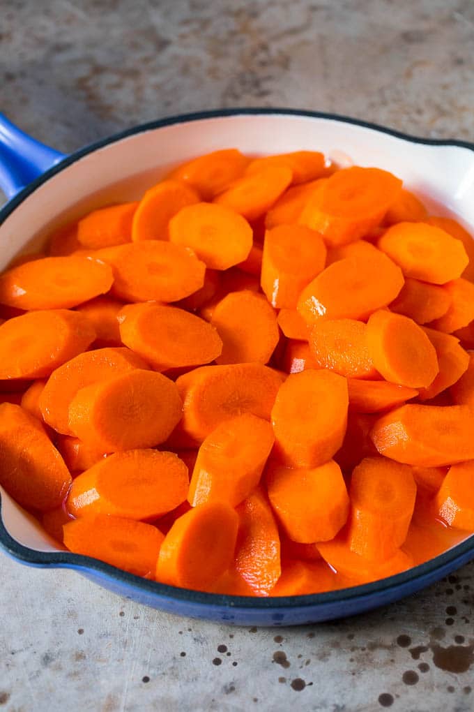 Sliced carrots cooked in water in a pan.
