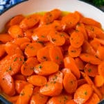 Honey glazed carrots in a blue pan, topped with parsley.