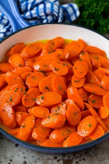 Honey glazed carrots in a blue pan, topped with parsley.