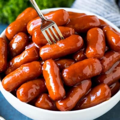 A bowl of crockpot little smokies with a fork in it.