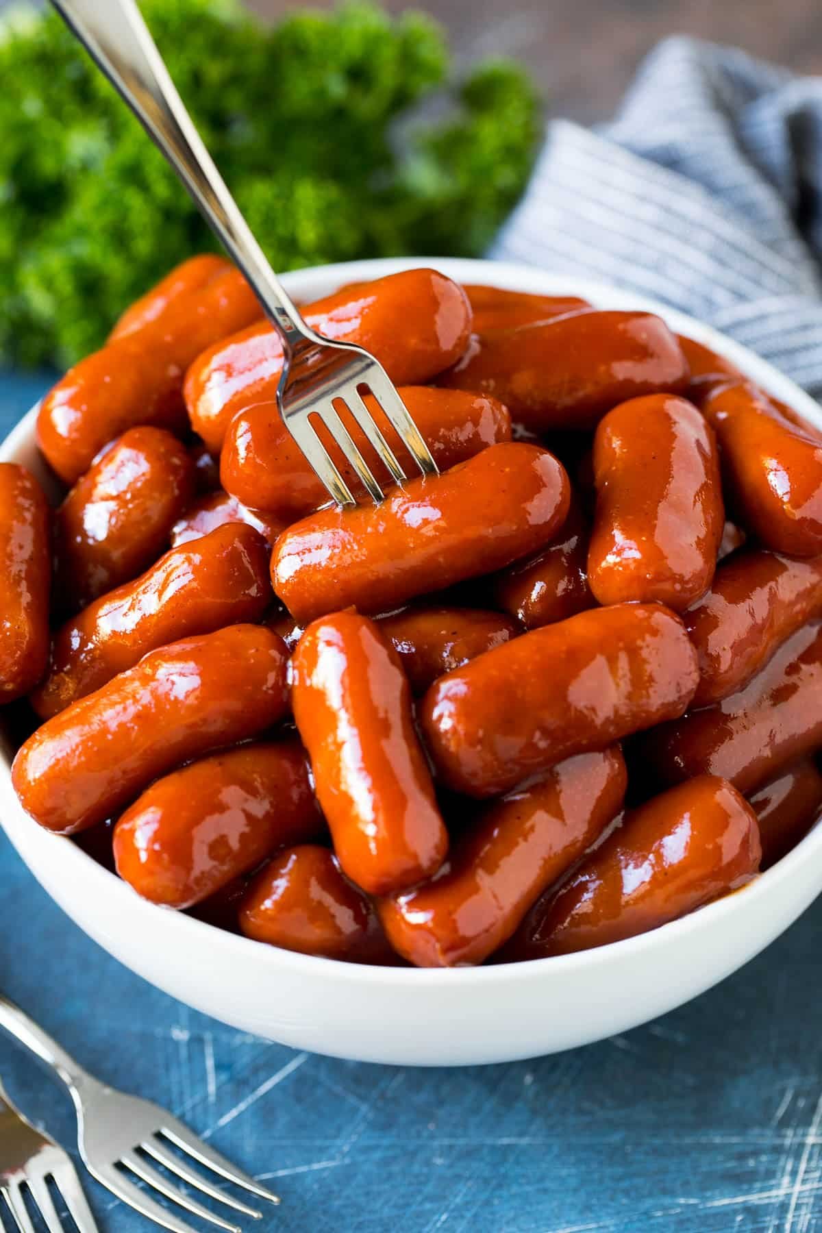 A bowl of crockpot little smokies with a fork in it.