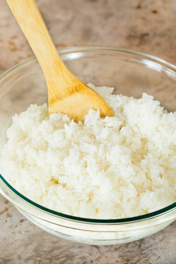 A bowl of seasoned rice with a paddle in it.