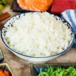 A bowl of sushi rice served with sashimi and seaweed salad.