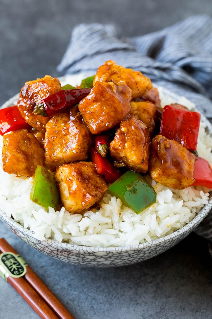 Szechuan chicken served over steamed rice in a bowl.