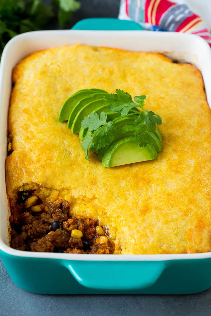 Tamale pie topped with sliced avocado and cilantro.