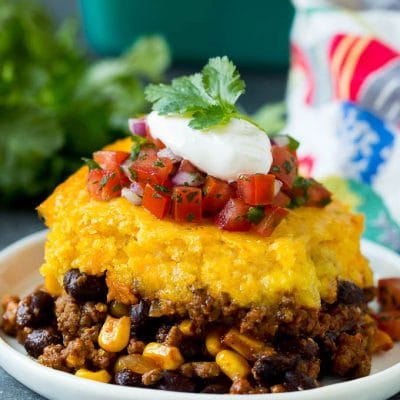A slice of tamale pie topped with salsa and sour cream.