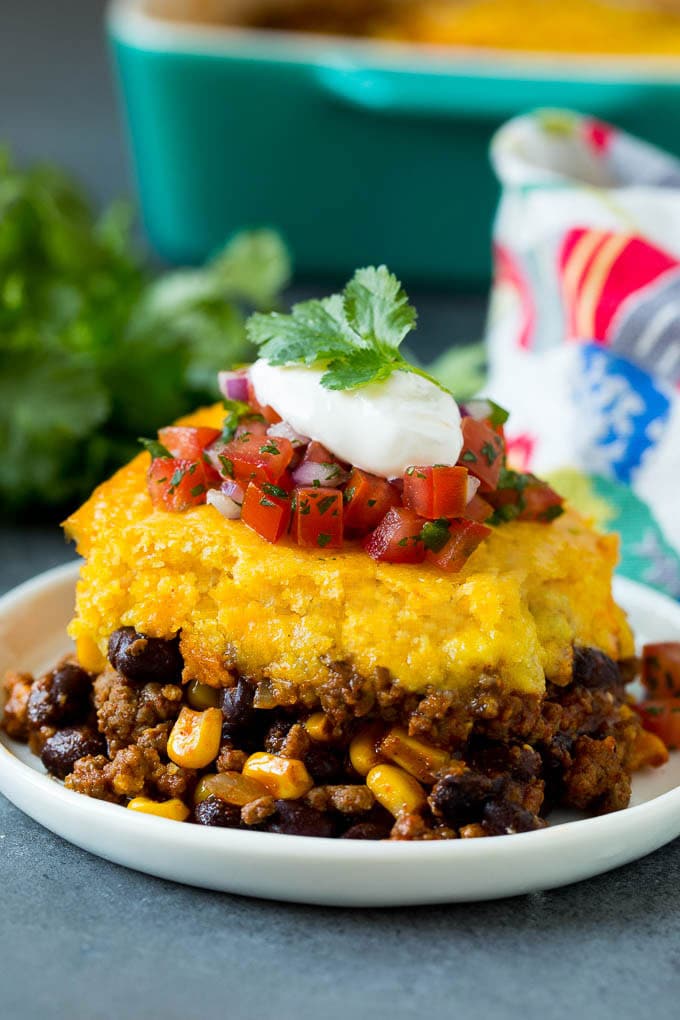 A slice of tamale pie topped with salsa and sour cream.