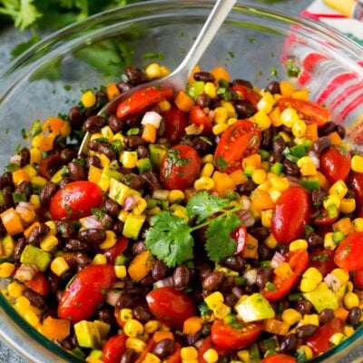 A bowl of black bean salad with a serving spoon in it.