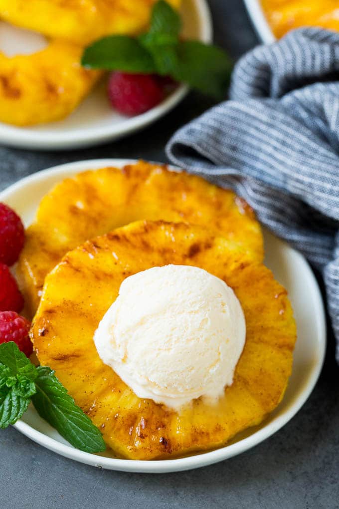 Grilled pineapple with a scoop of ice cream on top of it.