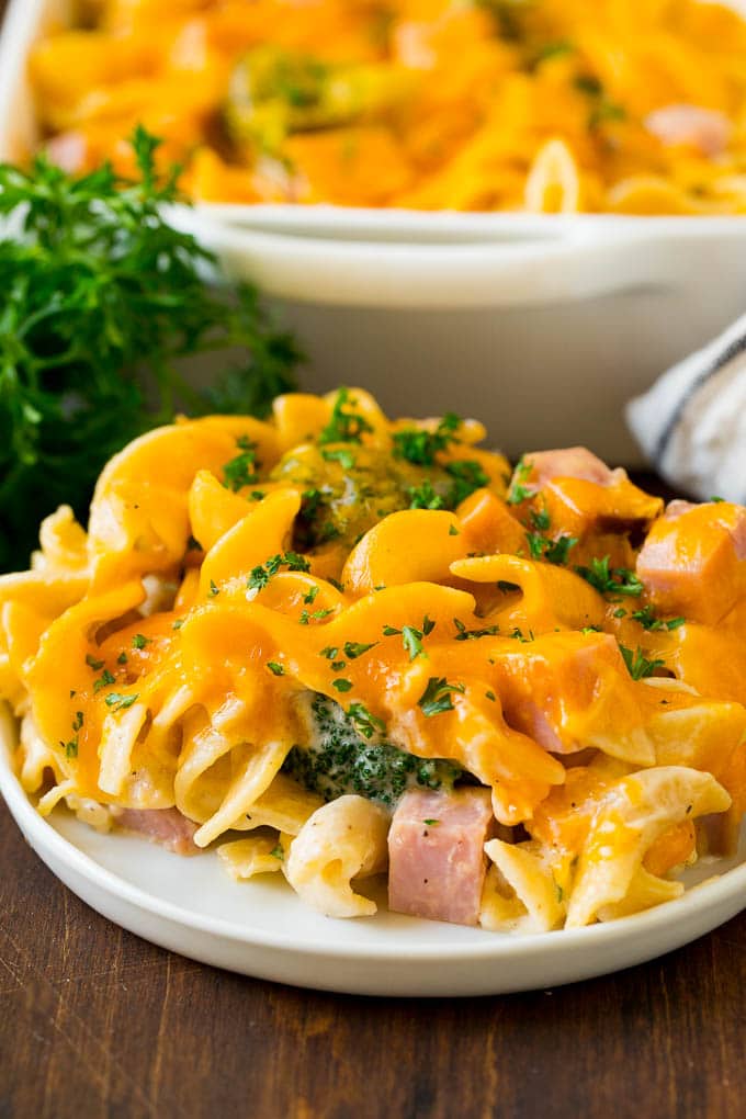 A serving of ham casserole on a plate, topped with melted cheese and chopped parsley.