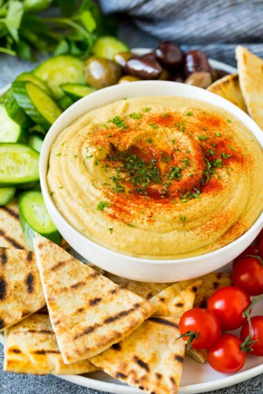 A bowl of homemade hummus served with pita and vegetables.
