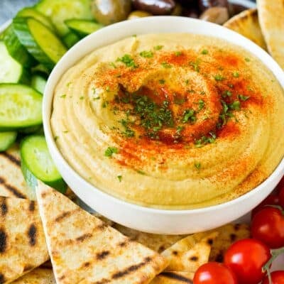 A bowl of homemade hummus served with pita and vegetables.