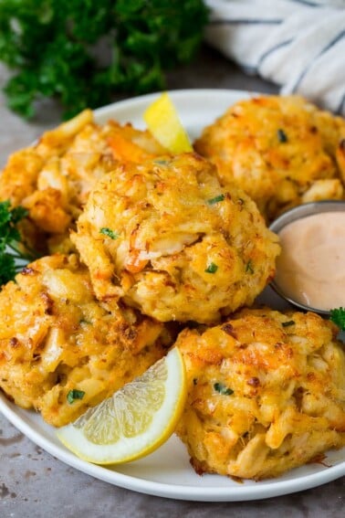 Maryland crab cakes on a serving plate with lemon wedges.
