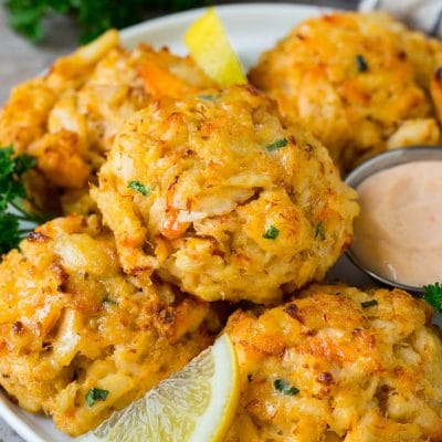 Maryland crab cakes on a serving plate with lemon wedges.