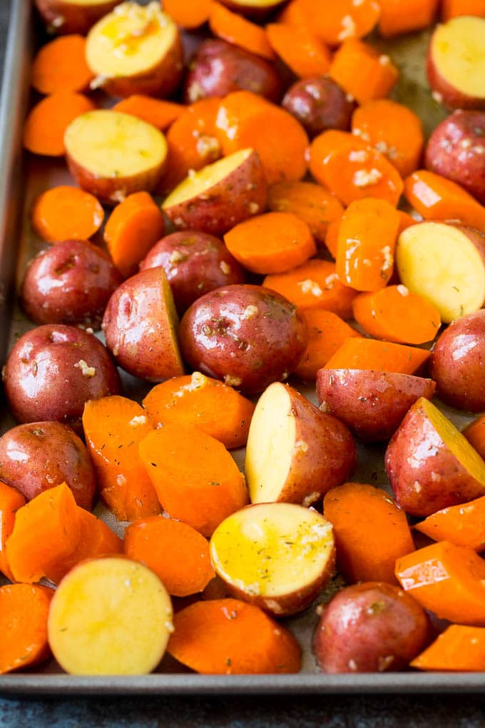 Vegetables spread out onto a sheet pan for baking.