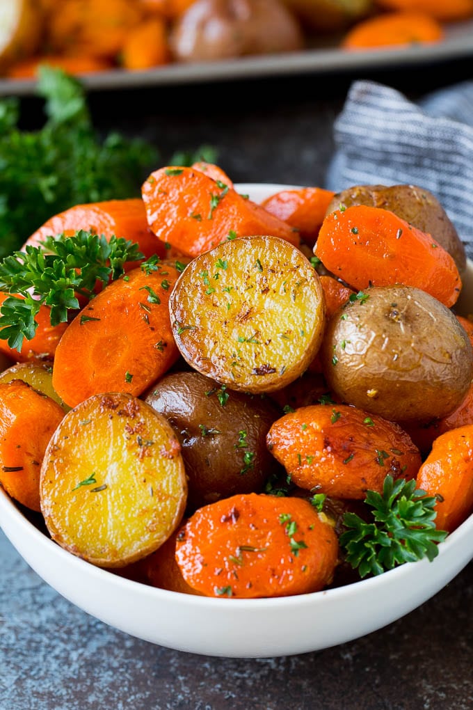 A bowl of roasted potatoes and carrots garnished with parsley.