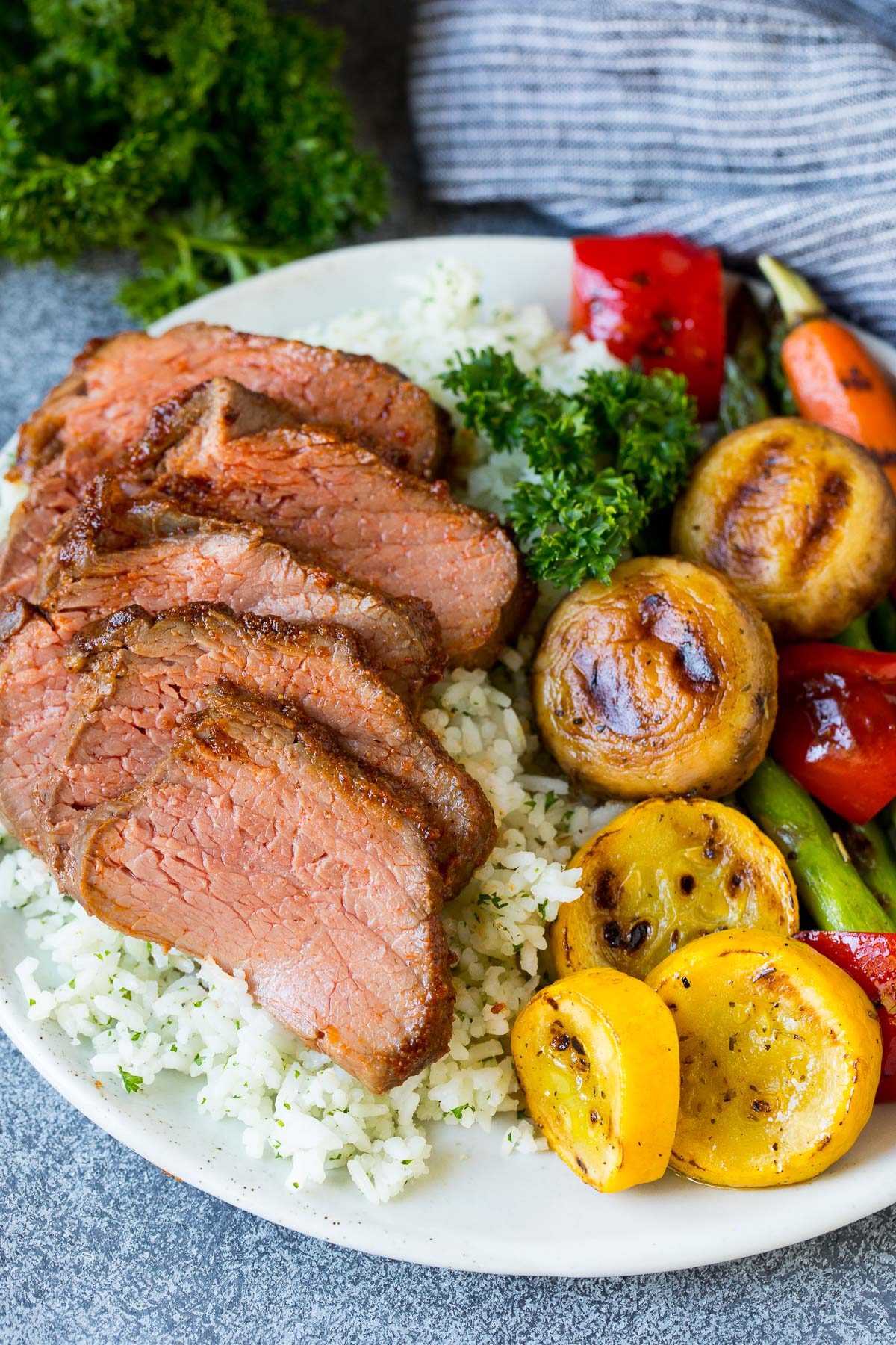 A plate of sliced smoked tri tip with rice and vegetables.